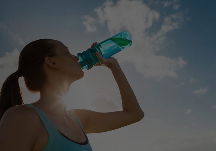 custom-website-design-company-newater-background-image woman drinking water from a bottle with the sun and sky in the background