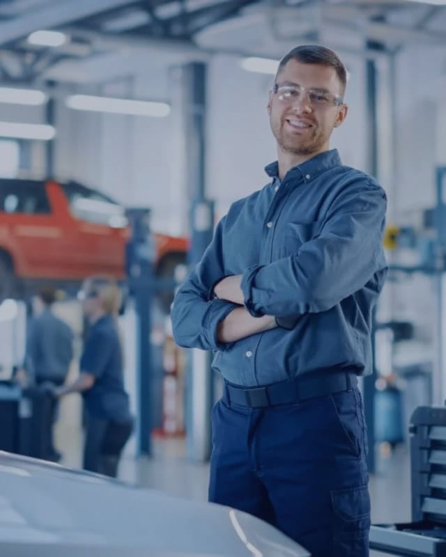 AAMCO-tall A man wearing a suit and protective glasses smiles at the camera