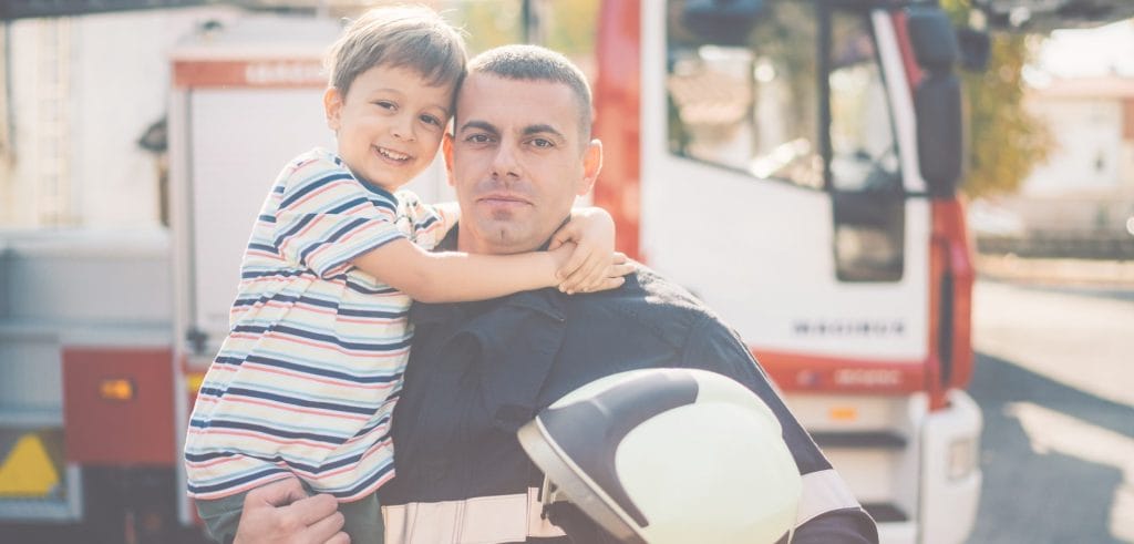 project-fire-buddies-background-1 Background image for Project Fire Buddies' case study showing a firefighter with his child in front of a fire truck