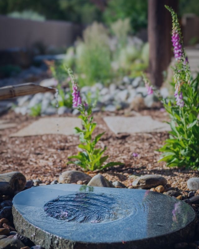 urbanna-background-4 Background image for Urbanna's case study showing a stone water basin with flowers around it in a landscaped garden